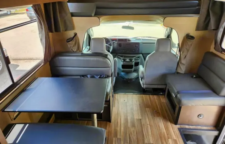 Spacious RV rental interior, showing dining table, bench seating, and front cabin.. Thor Majestic 2019