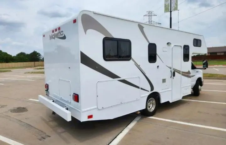 White Class C rv rental with brown accents, parked on asphalt. Perfect for your next road trip.. Thor Majestic 2019