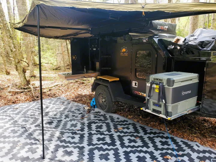 An RV rental overland trailer campsite with outdoor kitchen, Truma fridge, awning, and ground mat. Perfect for off-grid adventure!. Off Grid Trailers Off Grid Trailers Trailer 2021