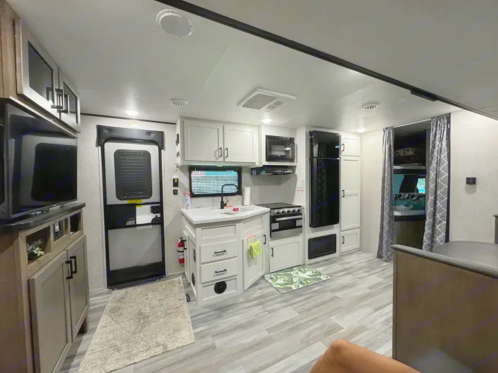 RV rental interior with modern kitchen island, stove, fridge, TV area, and bunks, all well-lit.. Jayco Jay Flight 261BHS 2024