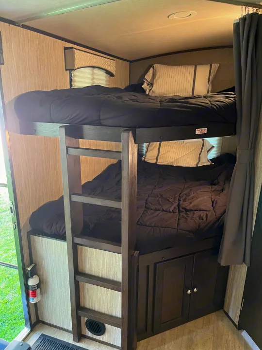RV rental interior: two stacked bunk beds with dark bedding provide compact sleeping. Notice the max weight label & fire extinguisher.. Cruiser RV Shadow Cruiser 2019