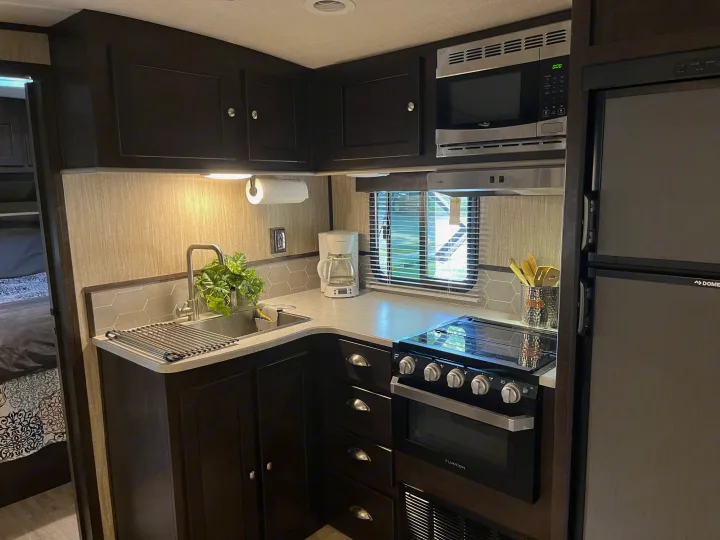 RV rental kitchen interior featuring modern appliances like a sink, stove, microwave, and refrigerator for comfortable travel.. Cruiser RV Shadow Cruiser 2019