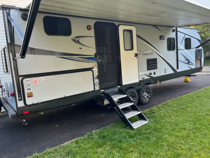 This spacious travel trailer, perfect for an rv rental adventure, is set up for camping with its steps down and awning out.. Cruiser RV Shadow Cruiser 2019