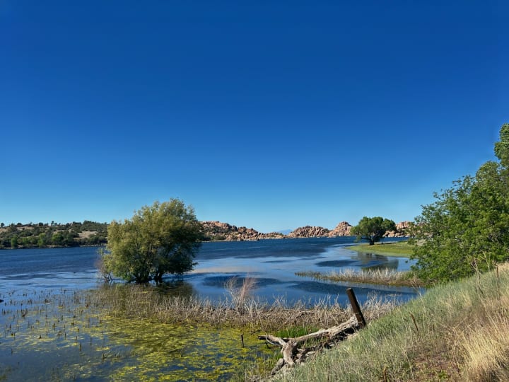 A scenic lake with unique rock formations, lush trees, and clear blue skies. Perfect for an RV rental getaway!. Grand Design Imagine XLS 2024