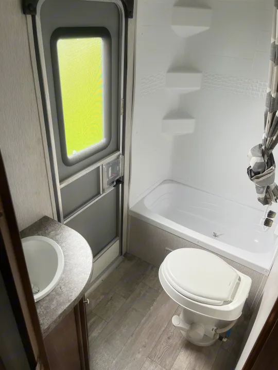 Inside an RV rental: a compact bathroom featuring a shower, toilet, and sink with modern finishes.. Pioneer Bunkhouse 2019