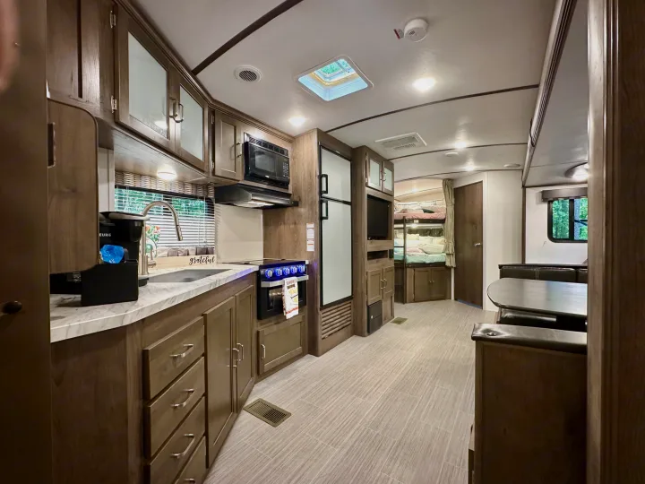 Spacious, modern RV rental interior featuring a full kitchen, dining area, and cozy bunk beds.. Keystone RV Passport Grand Touring 2020
