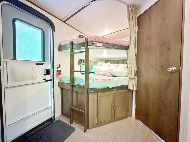 Cozy RV rental interior with bunk beds, ladder, entry door, and storage for family adventures.. Keystone RV Passport Grand Touring 2020