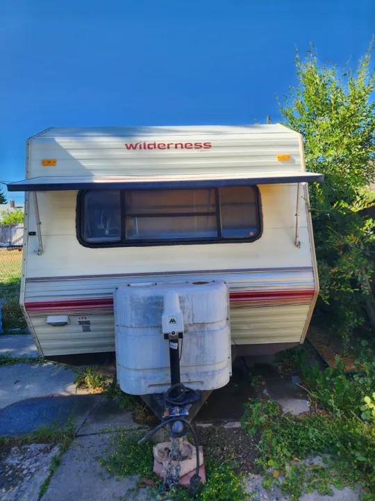 Front view of a cream 'Wilderness' travel trailer, ideal for an RV rental. Ready for your next camping or road trip adventure!. Fleetwood Wilderness 1991