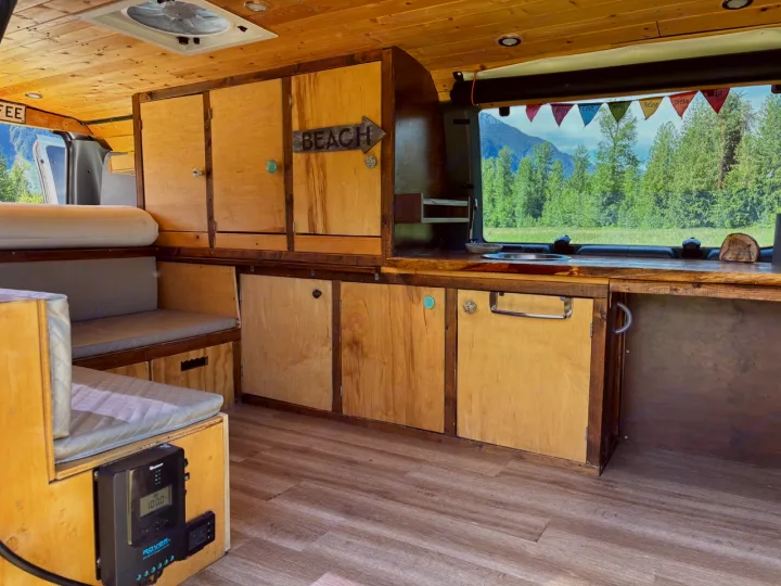 Custom wood interior of an RV rental: cozy living space with kitchen, seating & mountain views for your next adventure.. Ford Ford E350 1996