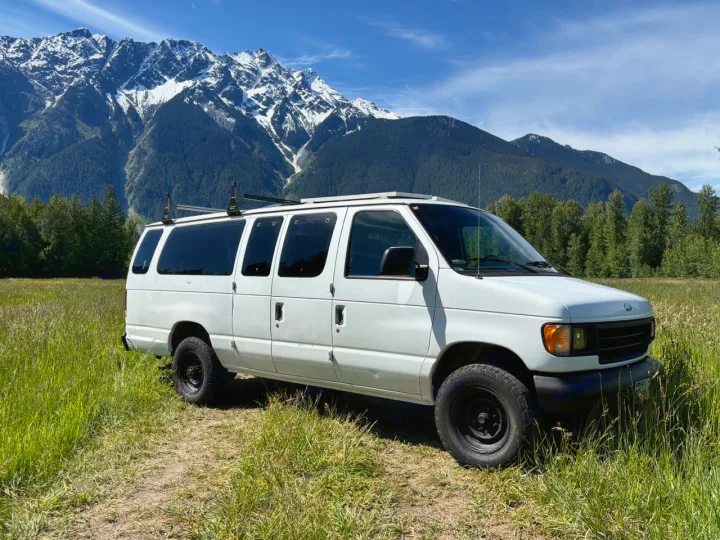 White Ford Econoline van, ideal for RV rental, parked in a scenic mountain landscape. Perfect for outdoor adventure.. Ford Ford E350 1996