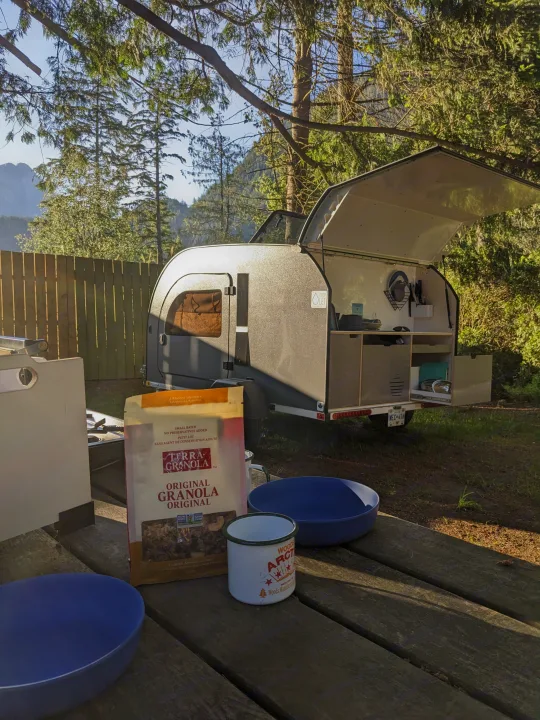 Morning at the campsite! Enjoying granola breakfast on a picnic table by our Droplet teardrop rv rental with its open outdoor kitchen.. DROPLET 58 2026