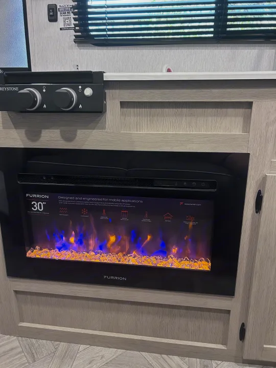Modern RV rental interior featuring a cozy electric fireplace and cooktop, designed for comfortable mobile living.. Forest River Salem Cruise Lite 2024