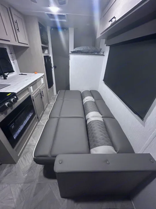 Stylish RV rental interior with a gray convertible sofa, kitchenette, and electric fireplace. Compact & comfy.. Forest River Salem Cruise Lite 2024