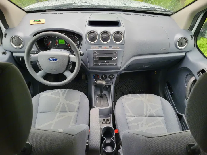 Ford Transit Connect van interior: dashboard, steering wheel, front seats, and automatic transmission. Ideal for an RV rental or work vehicle.. Ford Transit 2013