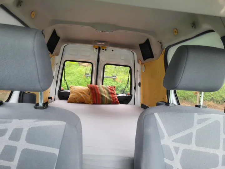 Cozy camper van interior with a bed and pillows, ready for adventure. Ideal for your next RV rental road trip or van life.. Ford Transit 2013