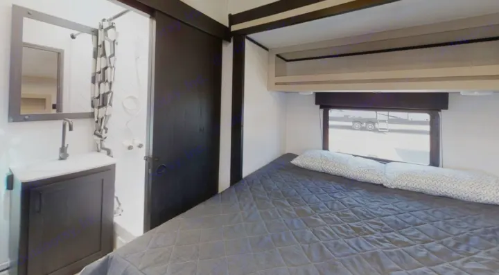 This RV rental features a cozy bedroom with a large bed, window, and overhead storage, plus a compact bathroom with a sink and shower.. Heartland RVs Fuel Toy Hauler 2021