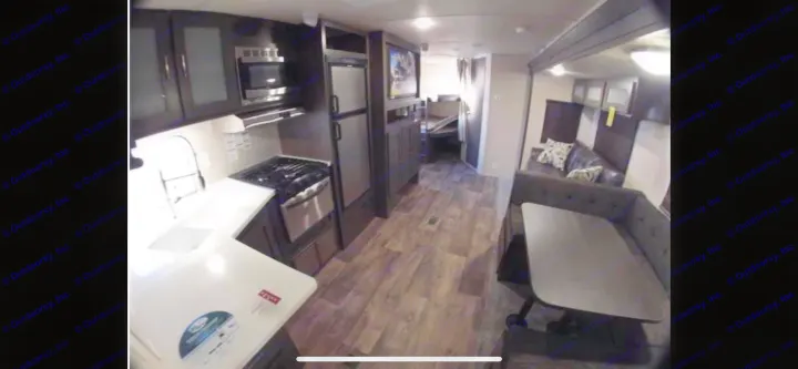 Spacious RV rental interior featuring a modern kitchen, dining booth, refrigerator, and a rear sleeping area with bunks.. Forest River Salem 2019