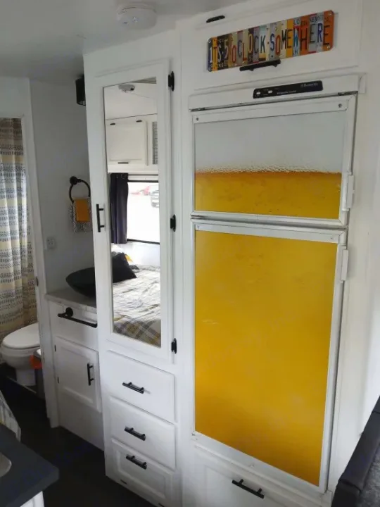 Bright RV rental interior features a playful 'beer' fridge, compact white cabinetry, and unique license plate sign.. Chevrolet Other 1996