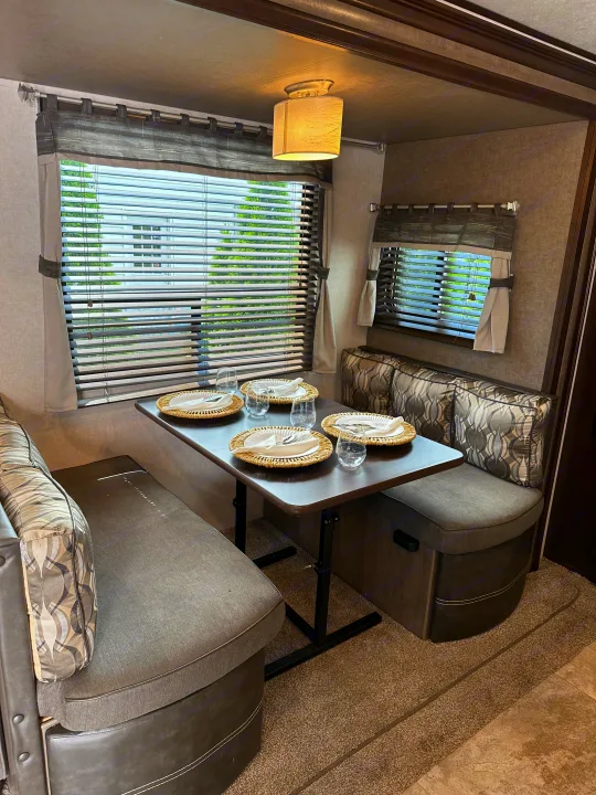 Well-appointed RV rental dinette ready for family meals. Blinds, curtains, and seating visible.. Forest River Surveyor 2018