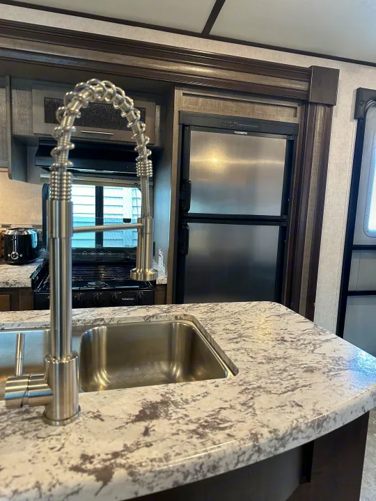 Modern RV rental kitchen featuring a large sink, Dometic fridge, and Suburban stove for comfortable travel.. Forest River Surveyor 2018