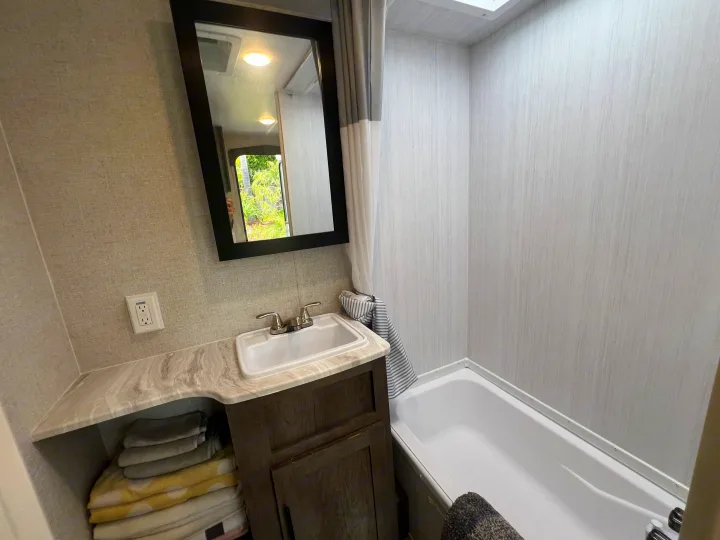 RV rental bathroom: sink, mirror, bathtub, and organized towels. Bright, clean space ready for your travels.. Forest River EVO 208RD 2021