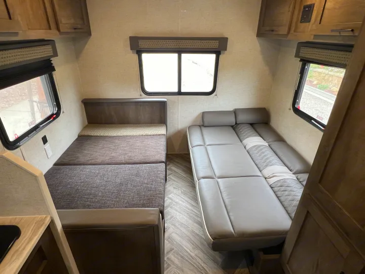 Inside an RV rental: versatile seating converts to beds on both sides, with windows and overhead storage for a cozy travel space.. Forest River EVO 208RD 2021