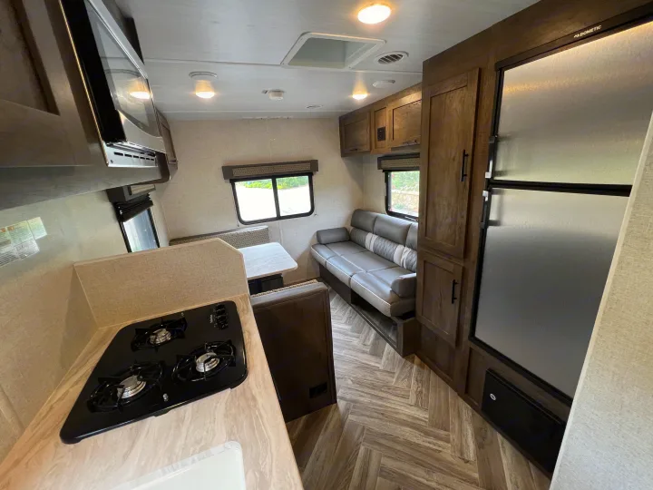 Full interior view of a modern **rv rental**, featuring a kitchen, dinette, comfortable sofa, and herringbone flooring.. Forest River EVO 208RD 2021