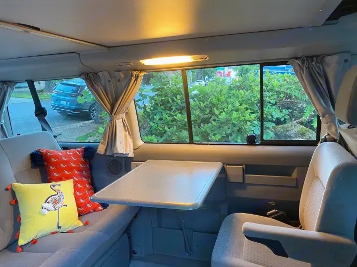 Step inside this cozy RV rental with a fold-out table, soft pillows, and scenic window views. Ideal for travel adventures!. Volkswagen Westfalia 2003