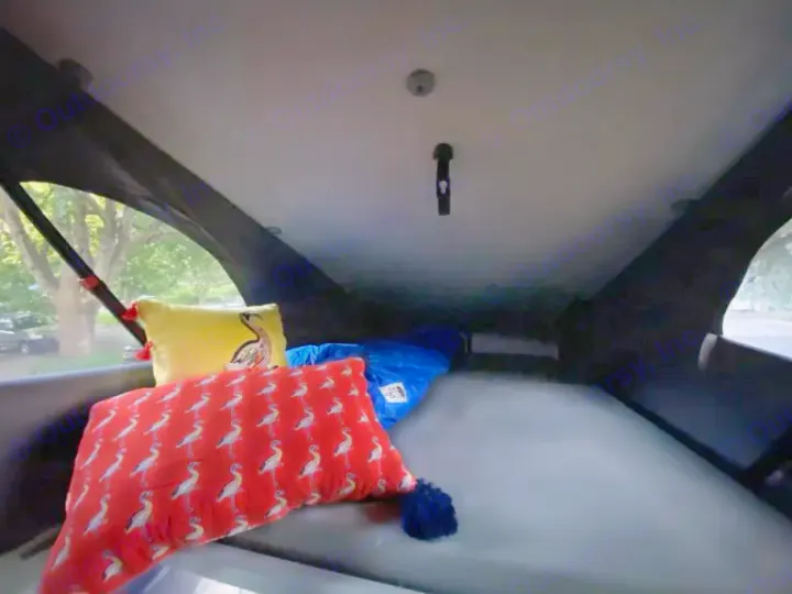Cozy RV rental pop-top camper interior. A bed with grey mattress, yellow & red bird-patterned pillows, and a blue sleeping bag.. Volkswagen Westfalia 2003
