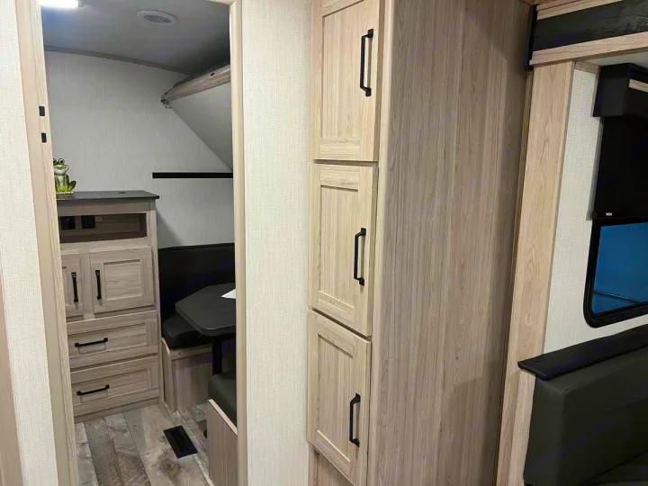 Cozy RV rental interior with light wood cabinetry, a dinette, bunk space, and storage solutions.. Heartland Sundance 2024