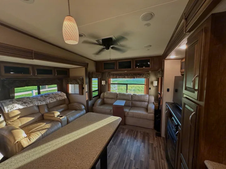 Inviting RV rental living space with leather recliners, wood-look floors, large windows, and modern ceiling fan.. Forest River Coachmen Chapparal 2016