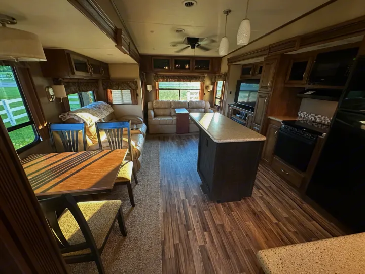 Spacious RV rental interior: living area with sofa, dining table, and full kitchen. Enjoy comfortable travel amenities.. Forest River Coachmen Chapparal 2016