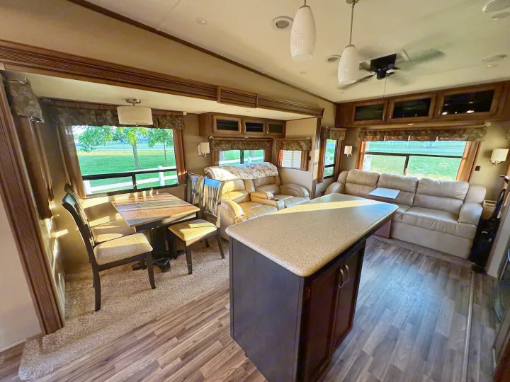 Spacious RV rental interior featuring a dining area, kitchen island, and plush sofas, ideal for comfortable travel.. Forest River Coachmen Chapparal 2016