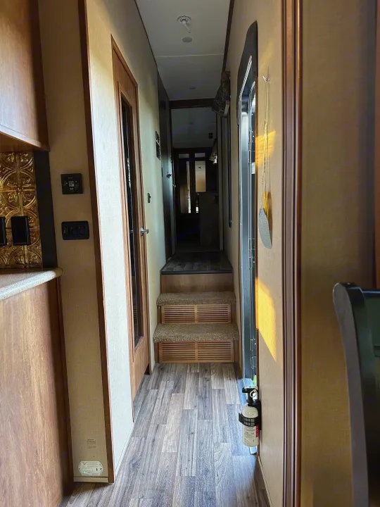 This RV rental features a well-lit interior hallway with steps, a fire extinguisher, and control panels by the counter.. Forest River Coachmen Chapparal 2016
