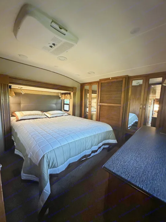 Spacious RV rental bedroom with a comfortable bed, mirrored wardrobes, and an AC unit, perfect for your next trip.. Forest River Coachmen Chapparal 2016