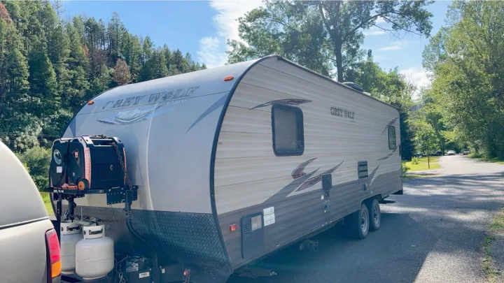 A large Grey Wolf travel trailer, potentially an RV rental, is parked outdoors with a generator and propane tanks. Ideal for camping.. Forest River Cherokee Grey Wolf Toy Hauler 2016