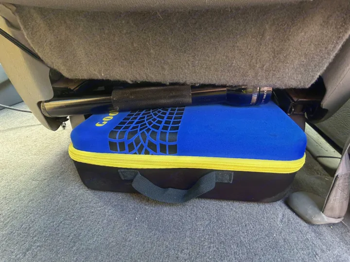 Blue Goodyear storage case with tire tread pattern and metal bar neatly stored under an RV rental seat.. Dodge Caravan 2003