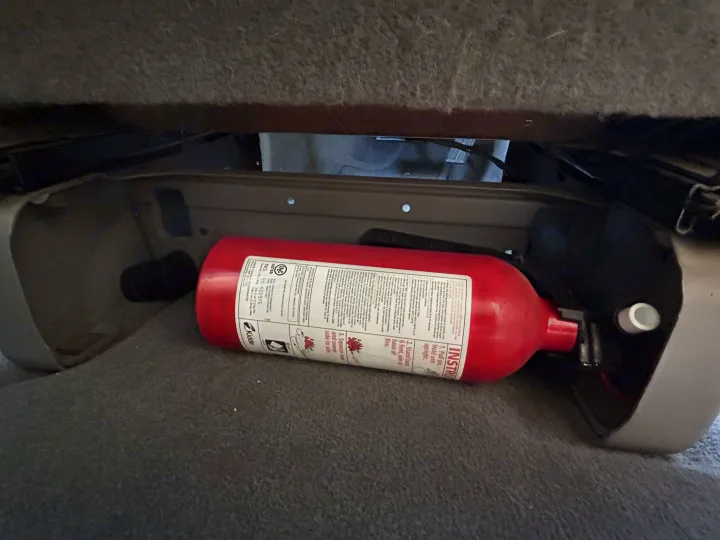 Essential RV rental safety: A red fire extinguisher stored under a seat, ready for road trip emergencies.. Dodge Caravan 2003