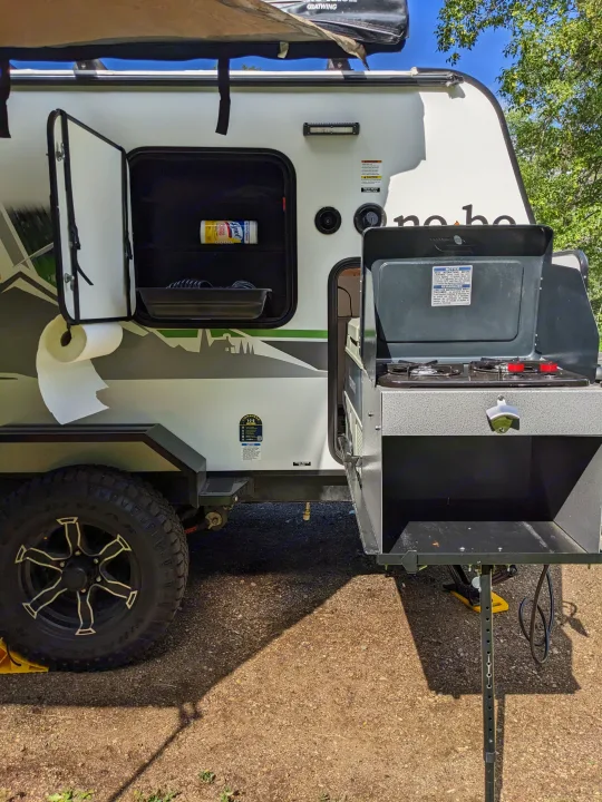This RV rental features an outdoor kitchen with a stove, handy storage, and a rugged tire, ready for adventure.. Forest River 10.6 no boundaries 2022