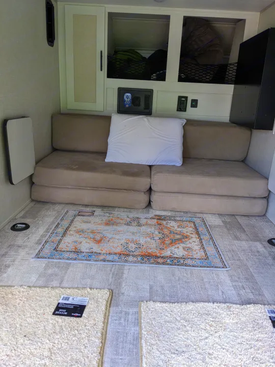RV rental living space with a convertible sofa bed, overhead storage, and layered floor rugs.. Forest River 10.6 no boundaries 2022