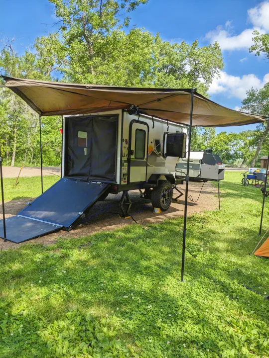 This RV rental camper is set up for outdoor adventures at a serene campsite with an extended awning and grill.. Forest River 10.6 no boundaries 2022
