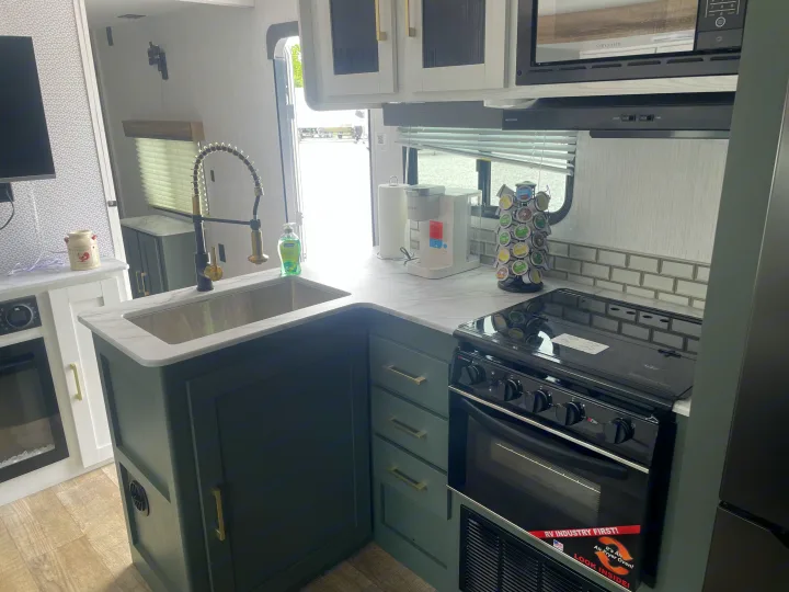 Explore this stylish RV rental kitchen! Features dark cabinets, a modern sink, air fryer oven, microwave, and coffee maker.. Keystone RV Eddie Bauer 34bsbh 2024