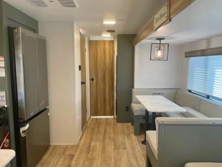 Inside a modern RV rental: kitchen with fridge, and U-shaped dinette. Bright, welcoming living space for your trip.. Keystone RV Eddie Bauer 34bsbh 2024