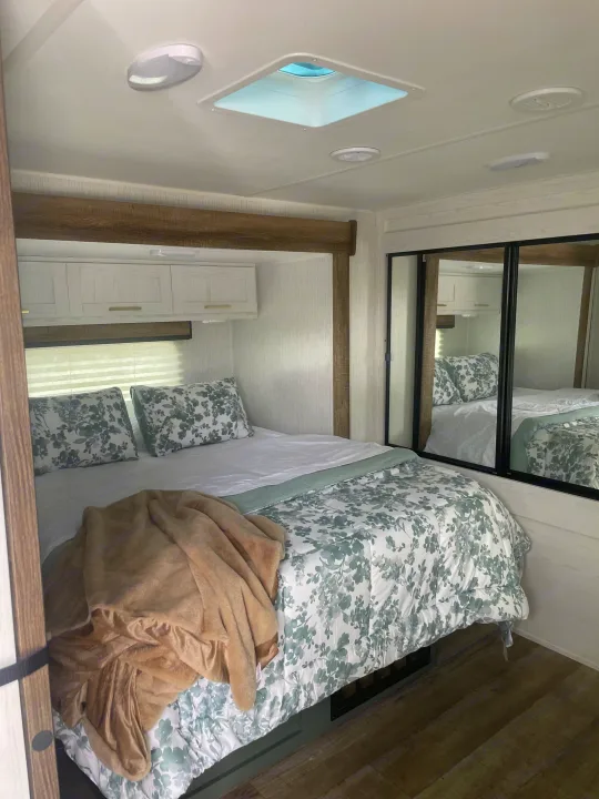 Cozy RV rental bedroom: features floral bedding, overhead lights, a skylight, and mirrored closets.. Keystone RV Eddie Bauer 34bsbh 2024