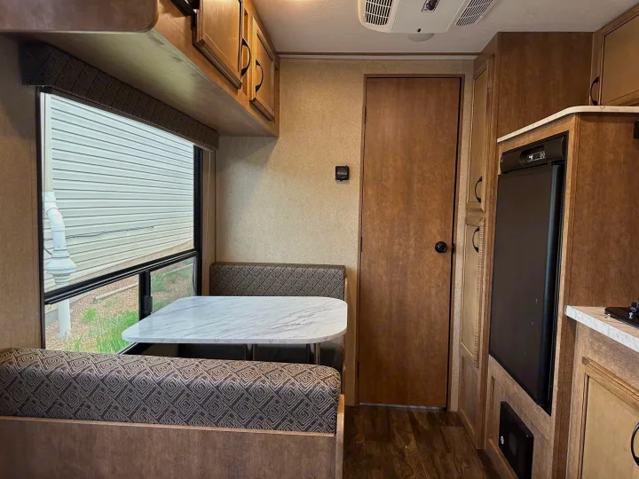 Spacious RV rental interior featuring a cozy dinette, modern kitchen with fridge, ample cabinets, and wood-look flooring.. Starcraft Launch Outfitter Extreme 2018
