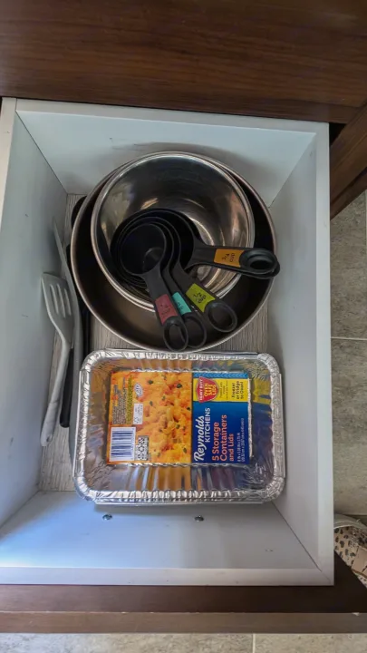 Kitchen drawer in an RV rental, with mixing bowls, measuring cups, spatula, and foil storage containers.. Heartland RVs Mallard 2019