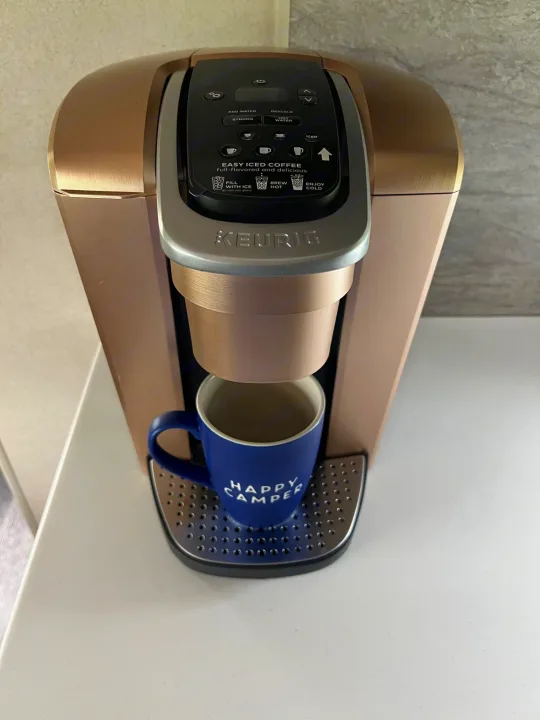 A rose gold Keurig coffee maker with a blue "Happy Camper" mug. Essential for your next RV rental trip!. Forest River Salem 2019