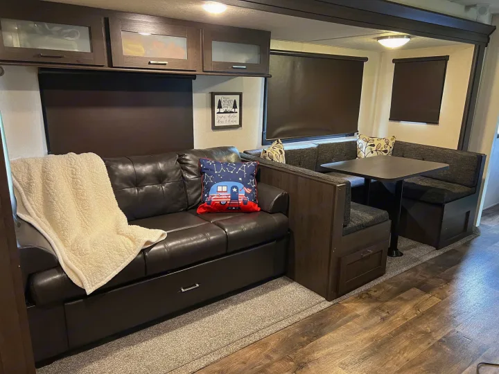 Inside a comfortable RV rental, featuring a dark leather sofa, cozy dinette, and overhead cabinets for storage.. Forest River Salem 2019