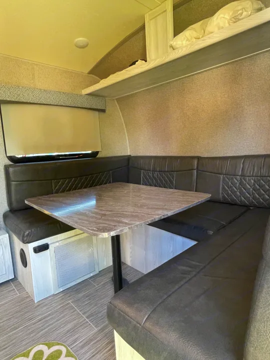 Inside an RV rental: a cozy dinette featuring U-shaped booth, table, and an upper bunk, ideal for dining and rest.. Forest River Rockwood Geo Pro 2018