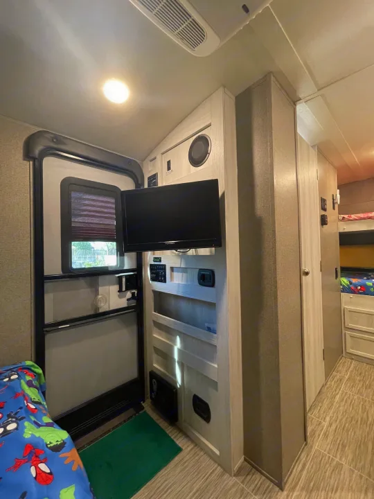 RV rental interior: entry door, mounted TV, bunk beds. Cozy space for travel adventures.. Forest River Rockwood Geo Pro 2018